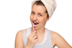 girl with a towel on her head brushing her teeth